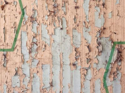 A photo of a wall with some heavily peeled and damaged paintwork, due to damp and mould damage